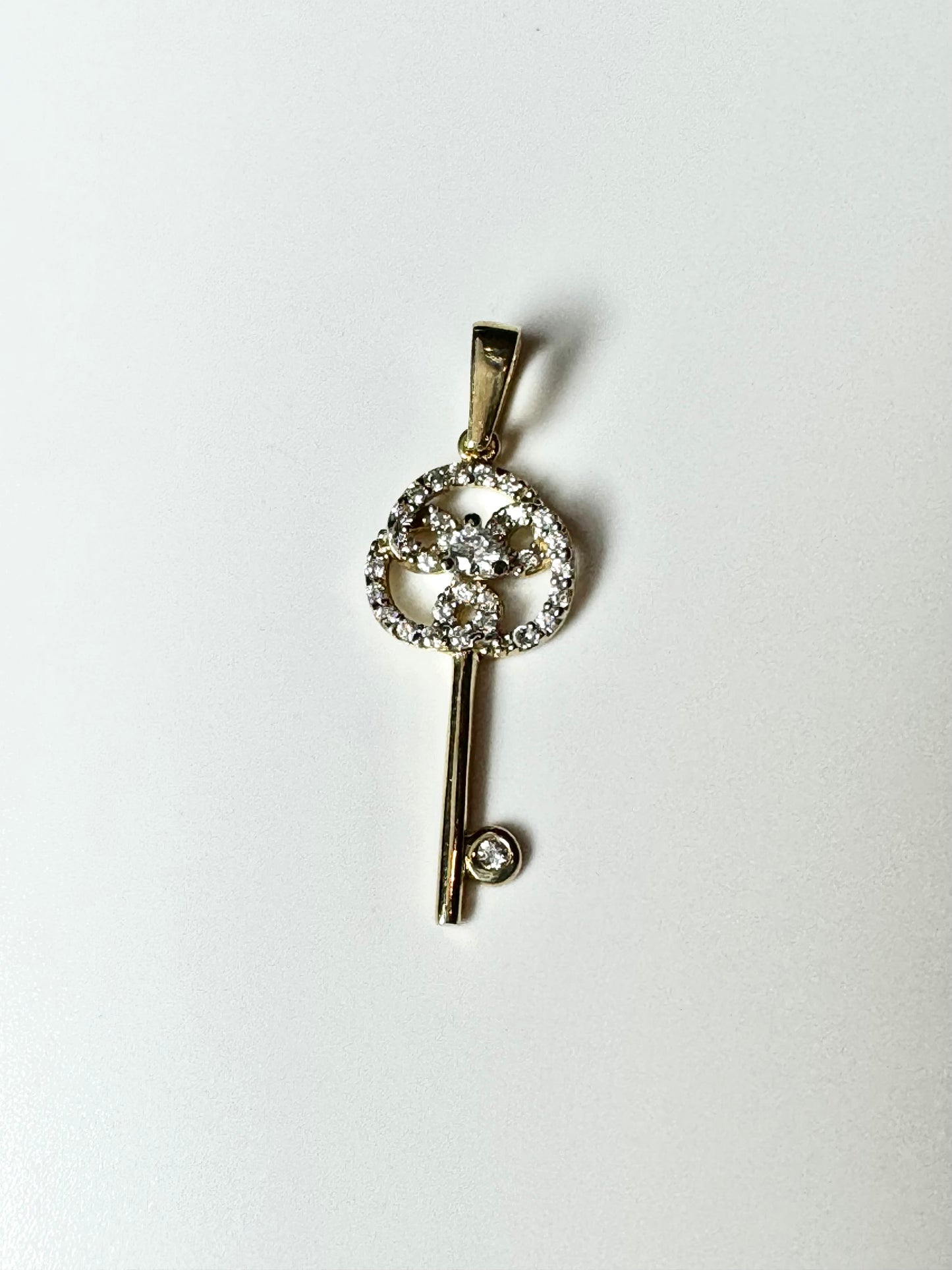 Gold key pendant with intertwined zircon