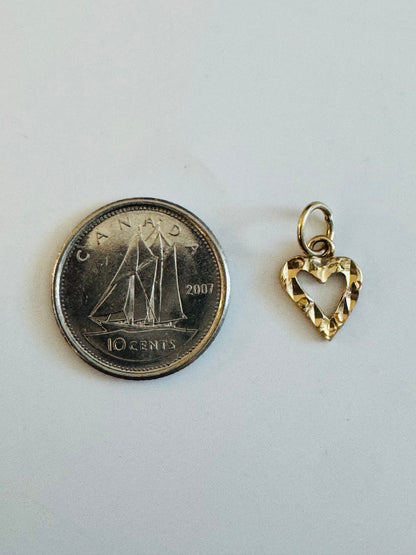 Pendentif petit cœur or 10k diamanté à côté d'une pièce de 10 cents pour échelle de taille.