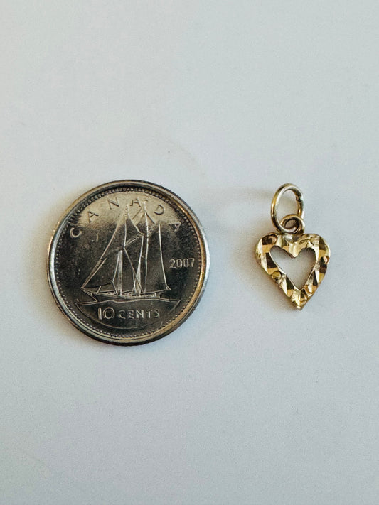 Pendentif petit cœur or 10k diamanté à côté d'une pièce de 10 cents pour échelle de taille.